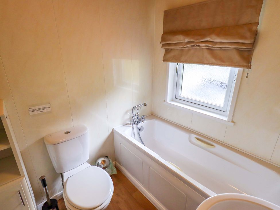 A bathroom with a toilet and bath at Birthwaite Lodge Fellside 6, Limefitt Park near Windermere