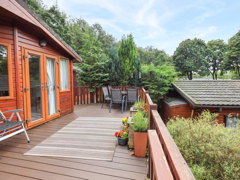 An outdoor deck with chairs and plants at Birthwaite Lodge, Fellside 6, Limefitt Park near Windermere