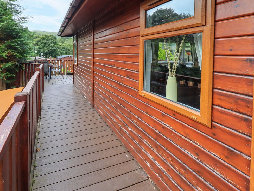 An outdoor view of a wooden deck with a window and a vase at Birthwaite Lodge, Fellside 6, Limefitt Park near Windermere