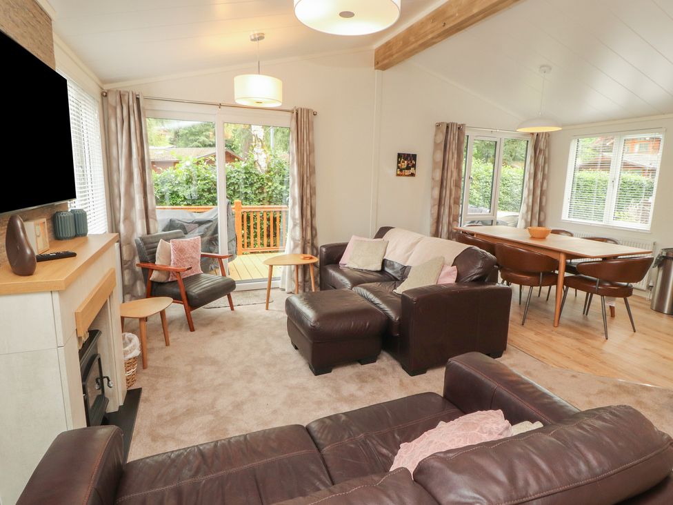 A living room with a sofa and dining area at Beech Grove Lodge, Glade 17, Fallbarrow Park near Bowness on Windermere