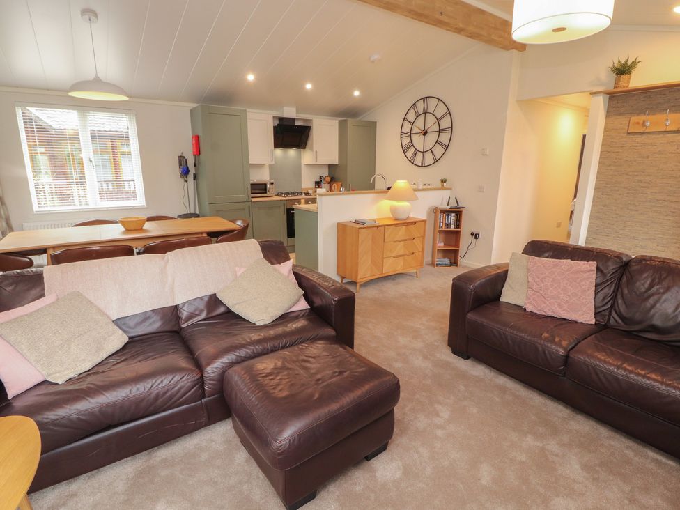 A living room with a sofa and dining table at Beech Grove Lodge, Glade 17, Fallbarrow Park near Bowness on Windermere