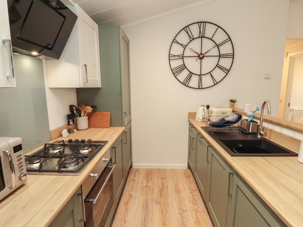 A kitchen with stove and sink at Beech Grove Lodge, Glade 17, Fallbarrow Park near Bowness on Windermere