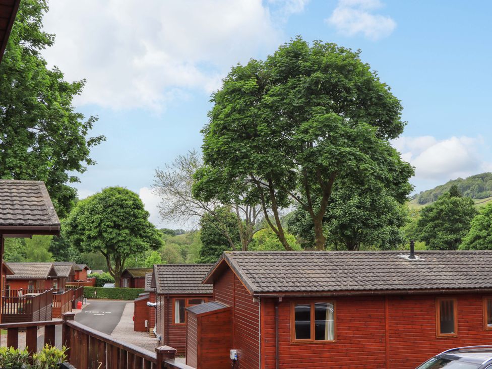 A view of wooden lodges and trees in a park setting at Pheasant's Nest Kirkstone 11 Limefitt Park near Windermere