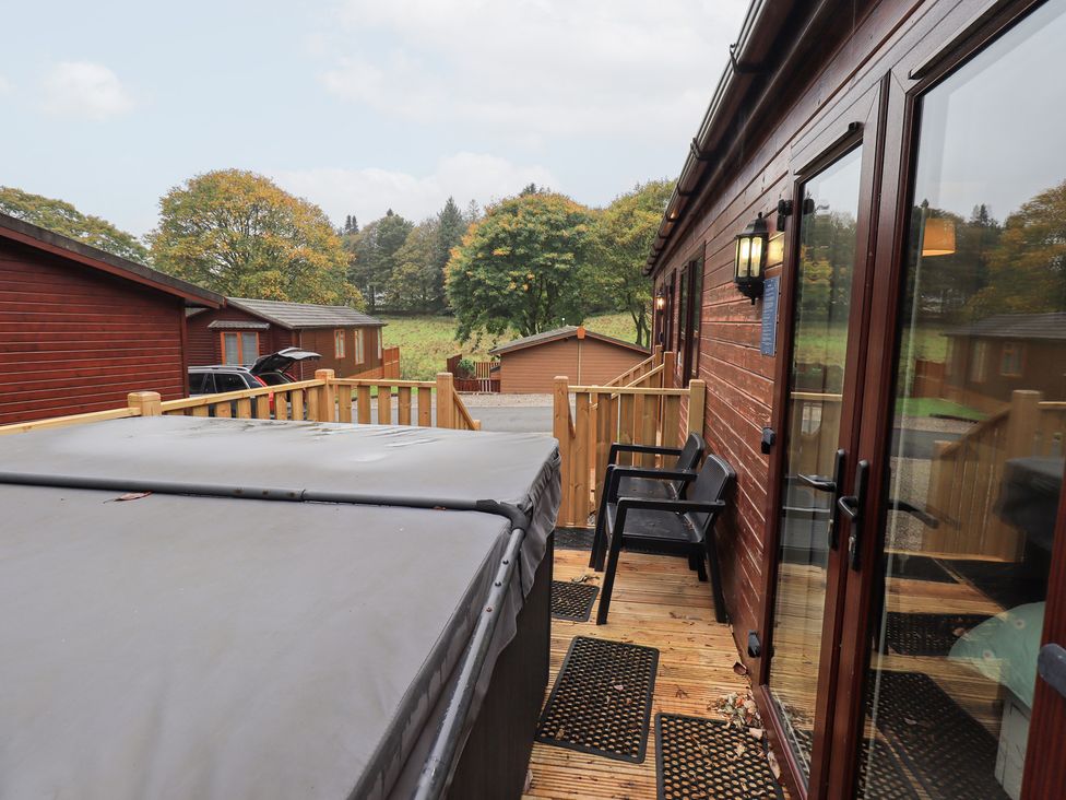 An outdoor area with a hot tub and chairs at Robin View Lodge, Beckside 3, Limefitt Park near Windermere