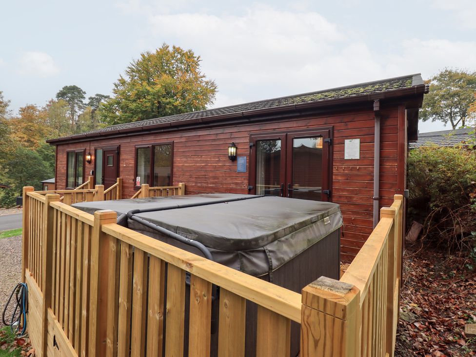A wooden lodge with a hot tub and fenced outdoor area at Robin View Lodge Beckside 3, Limefitt Park near Windermere