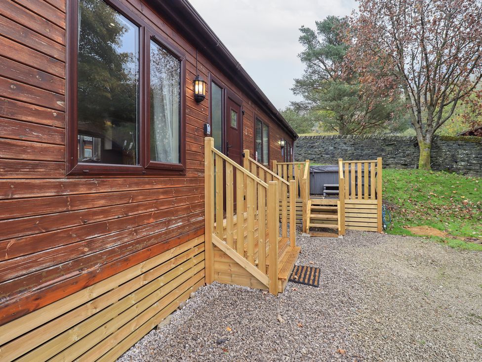 An exterior view of a wooden lodge with steps and gravel area at Robin View Lodge Beckside 3 Limefitt Park near Windermere