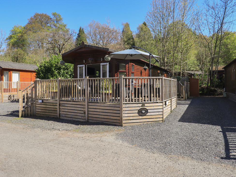 A lodge with a deck and umbrella at Badgers Hollow Lodge Grasmere 30 White Cross Bay near Windermere