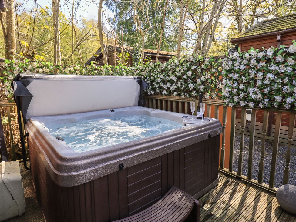 An outdoor hot tub surrounded by flowers at Badgers Hollow Lodge Grasmere 30, White Cross Bay near Windermere