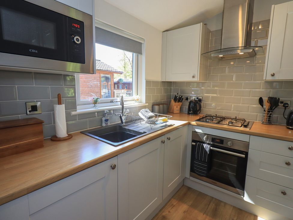 A kitchen with cabinets and appliances at Badgers Hollow Lodge Grasmere 30, White Cross Bay near Windermere