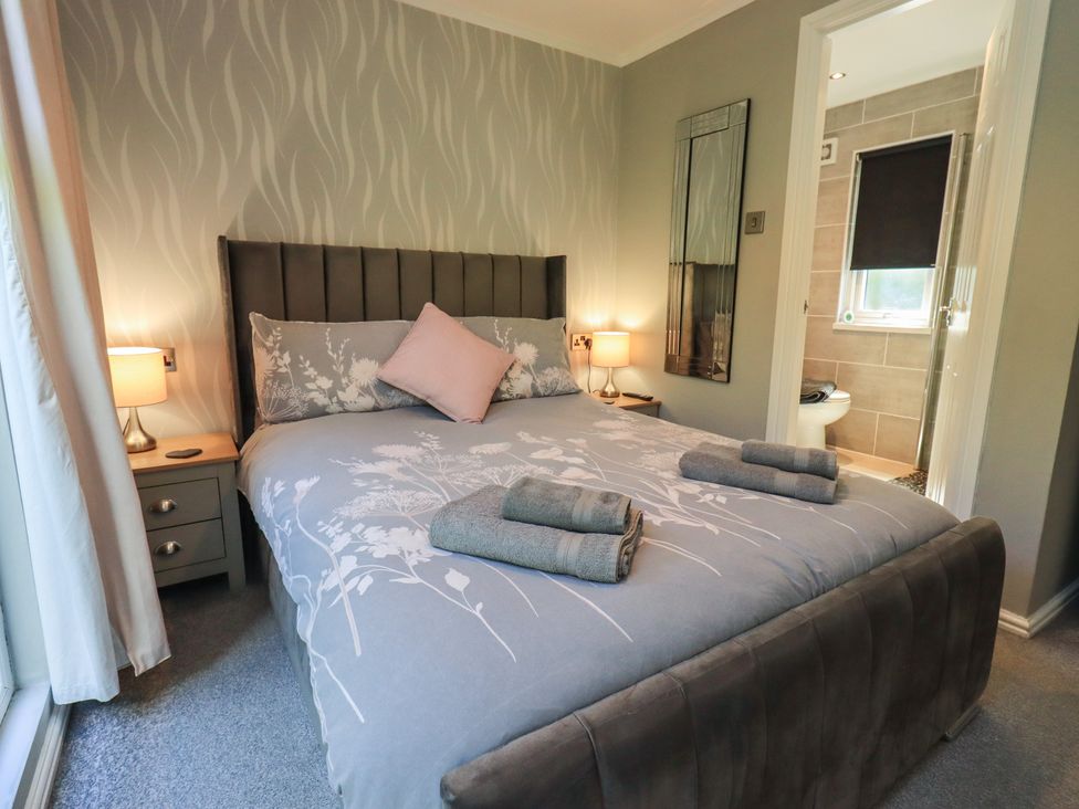 A bedroom with a bed and nightstand at Badgers Hollow Lodge, Grasmere 30, White Cross Bay near Windermere