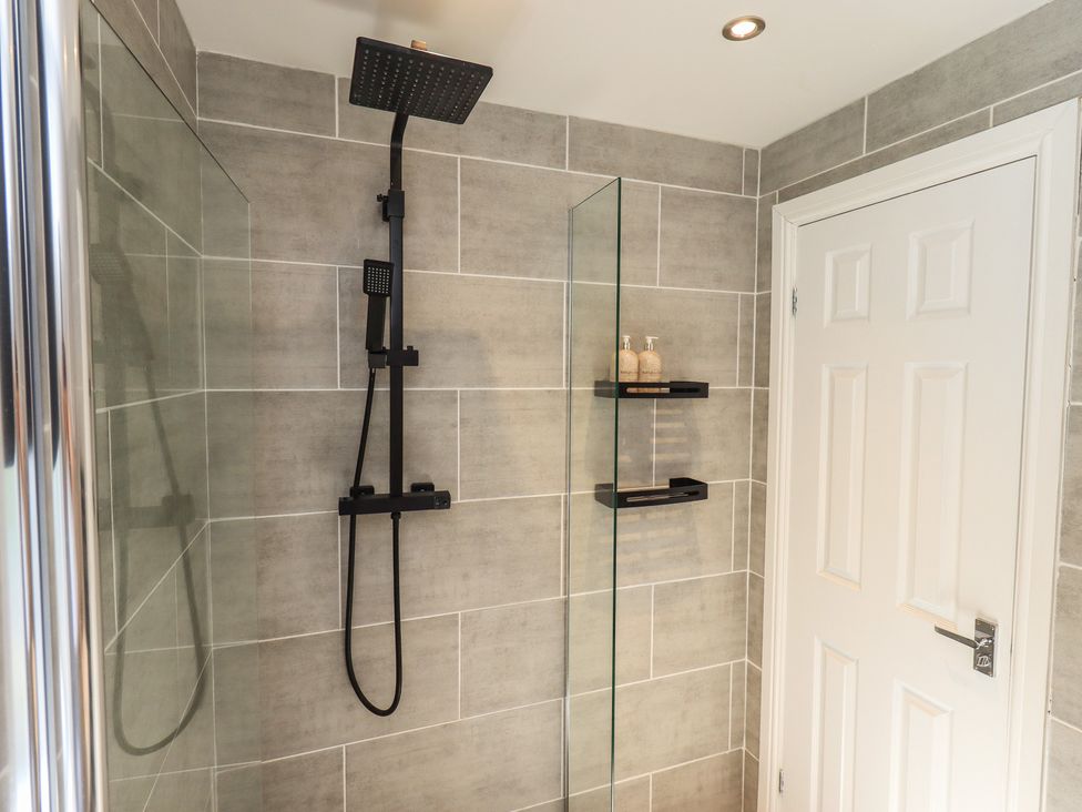 A shower with modern fixtures and a door at Badgers Hollow Lodge Grasmere 30, White Cross Bay near Windermere