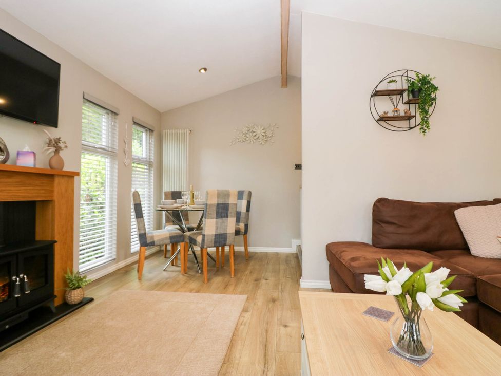A living room with a dining area and television at Badgers Hollow Lodge Grasmere 30, White Cross Bay near Windermere