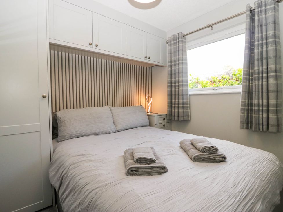 A bedroom with a bed and bedside table at Badgers Hollow Lodge Grasmere 30 White Cross Bay near Windermere
