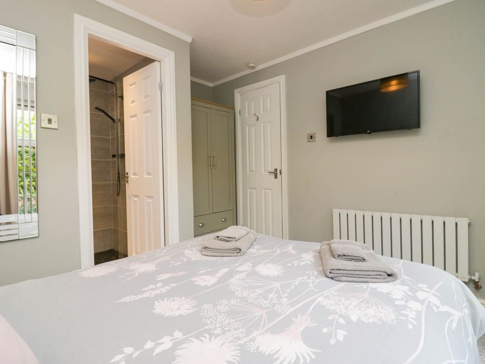 A bedroom with a bed and television at Badgers Hollow Lodge Grasmere 30 White Cross Bay near Windermere