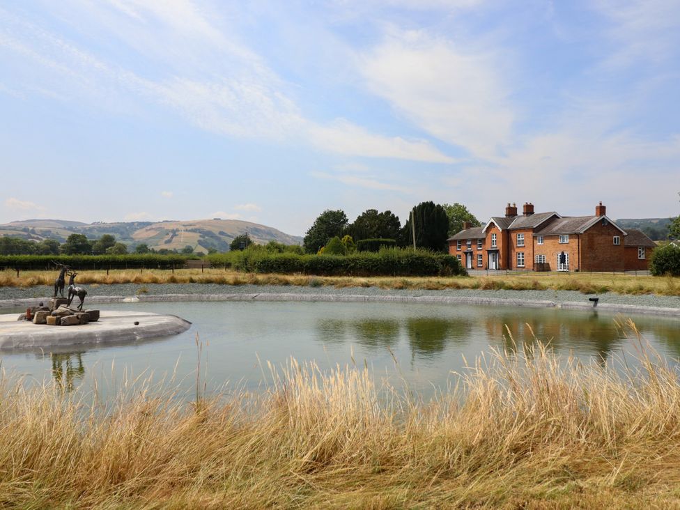 A house beside a pond with a statue at Bodaioch Hall Trefeglwys near Caersws