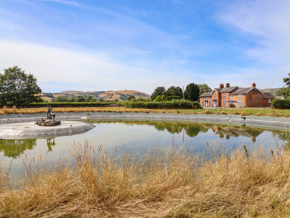 A house beside a pond with a statue at Bodaioch Hall Trefeglwys near Caersws