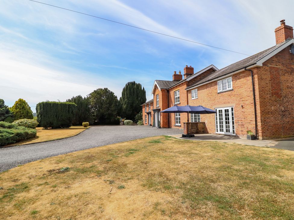 A house with a patio umbrella and garden area at Bodaioch Hall Trefeglwys near Caersws