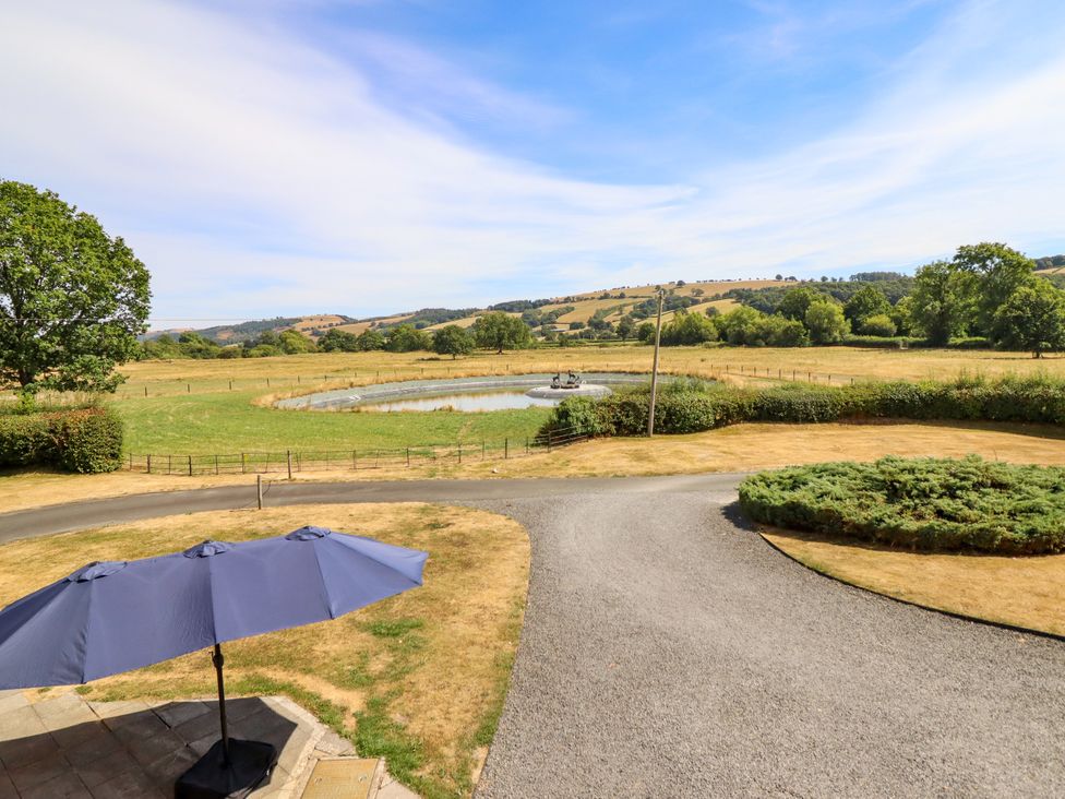 An outdoor area with a pond and fields at Bodaioch Hall Trefeglwys near Caersws