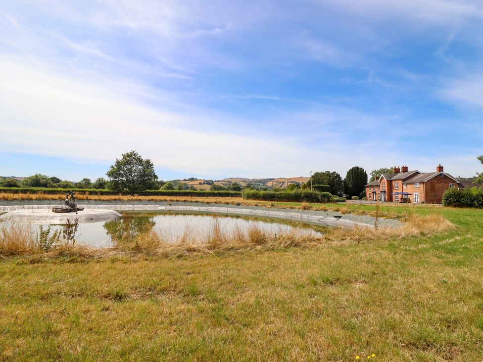 A house next to a pond and grassy area at Bodaioch Hall Trefeglwys near Caersws