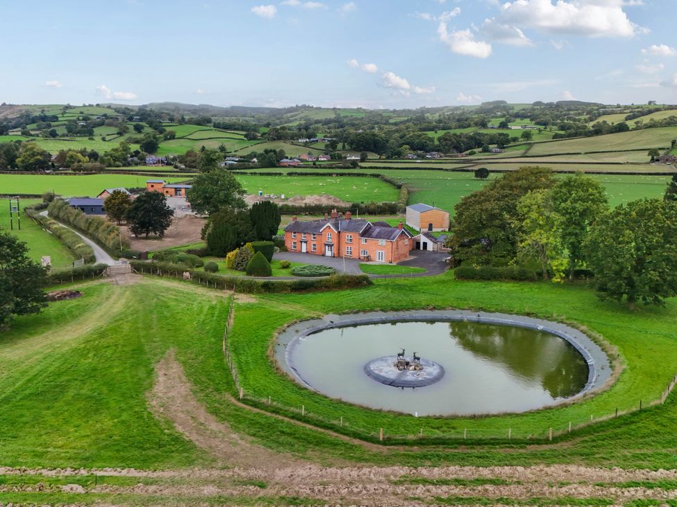 A house with a pond in front and fields around Bodaioch Hall Trefeglwys near Caersws