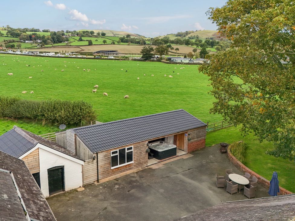 An outdoor area with a hot tub and seating at Bodaioch Hall Trefeglwys near Caersws