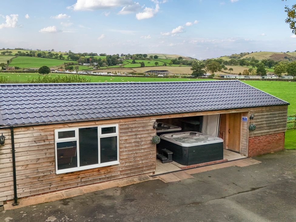 An outdoor view of a building with a hot tub at Bodaioch Hall Trefeglwys near Caersws