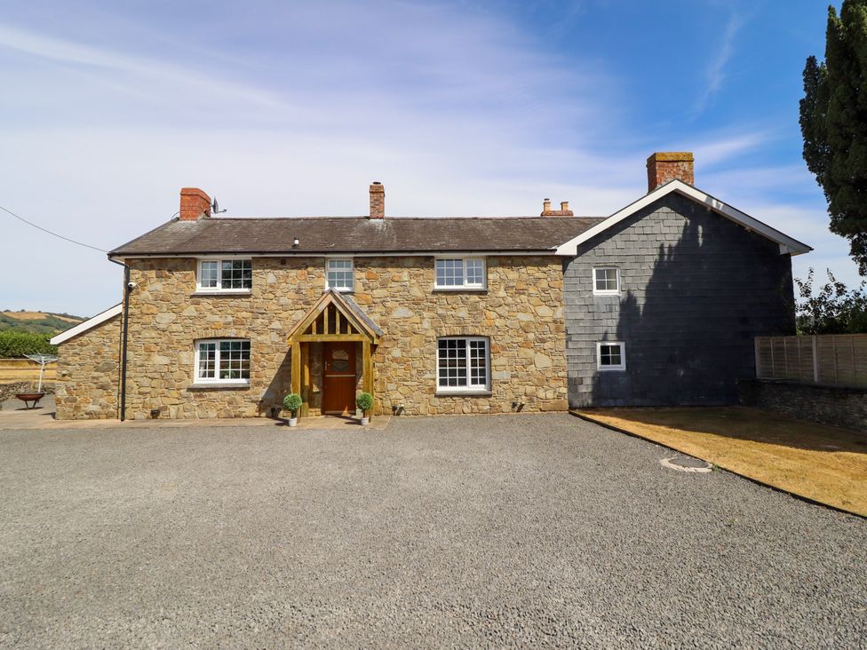 A stone house with a driveway and front entrance at Bodaioch Cottage in Trefeglwys near Caersws