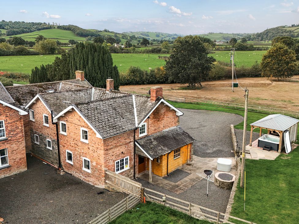 An outdoor view of a house with a gravel drive and a hot tub at Bodaioch Cottage in Trefeglwys near Caersws