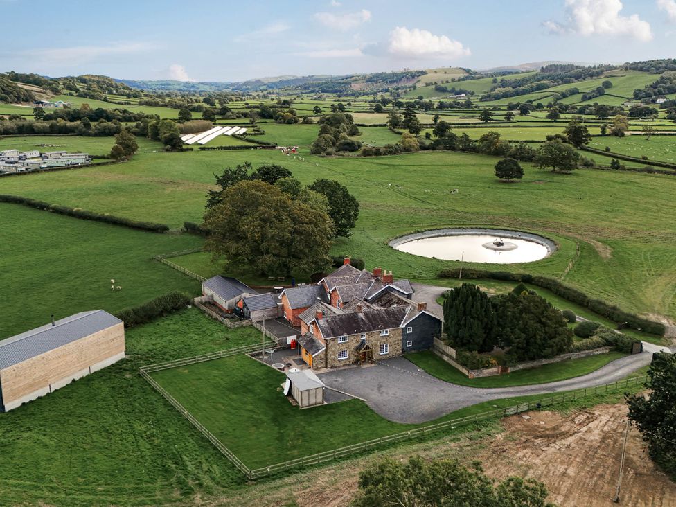 An aerial view of a house surrounded by fields and trees at Bodaioch Cottage Trefeglwys near Caersws