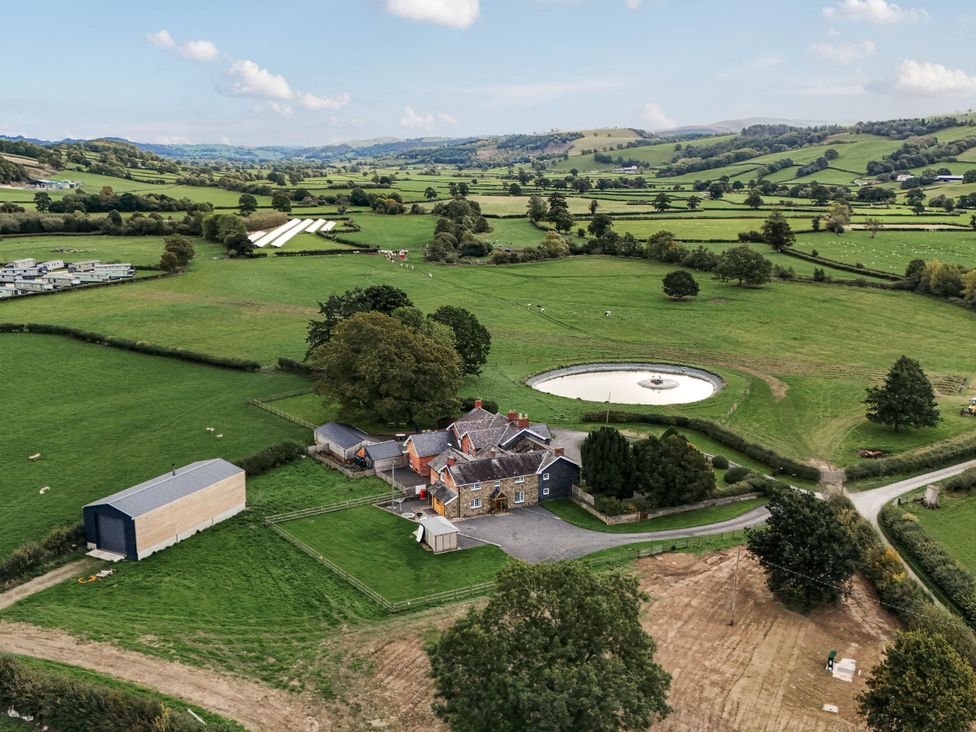 An aerial view of a house and barn with fields in Trefeglwys near Caersws Bodaioch Cottage