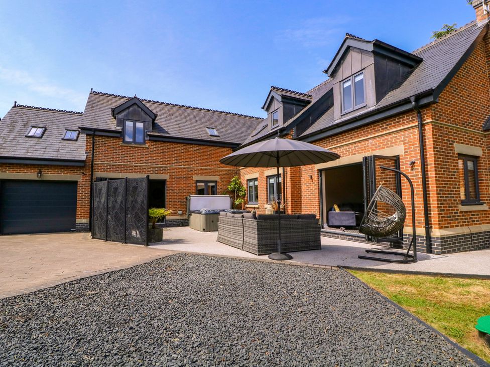 An outdoor patio area with seating and an umbrella at Thornbury, Barnard's Green, Malvern