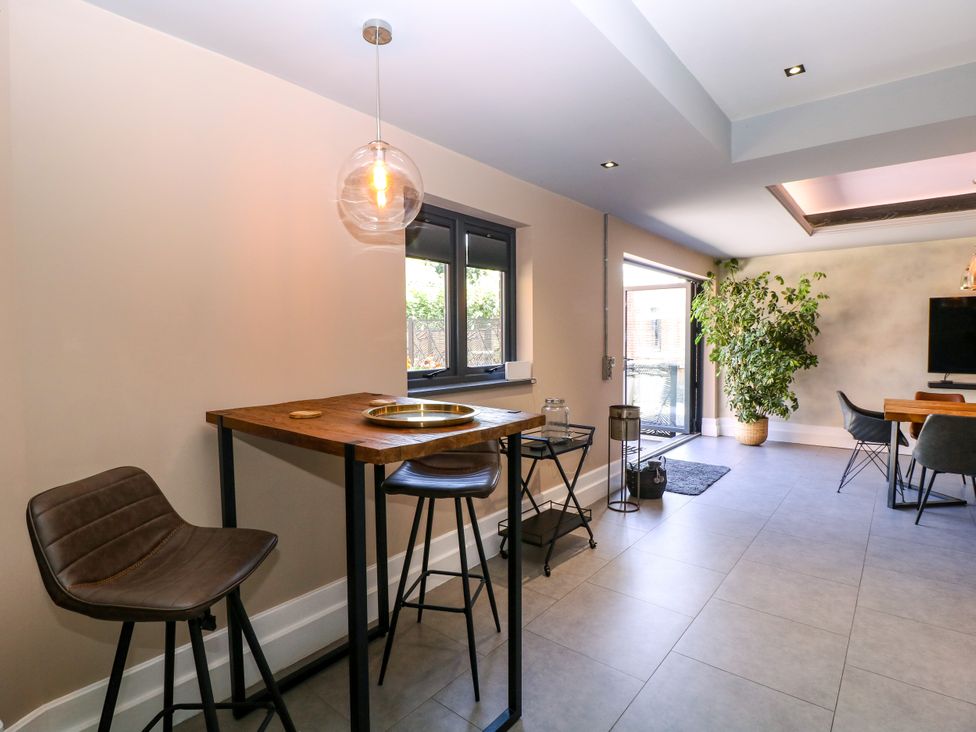 A dining room with a table and bar stools at Thornbury, Barnard's Green, Malvern