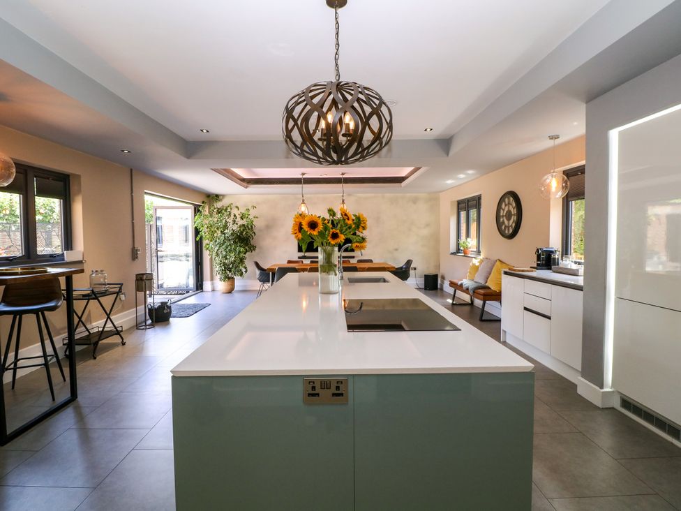 A kitchen with an island and bar stools at Thornbury, Barnard's Green, Malvern