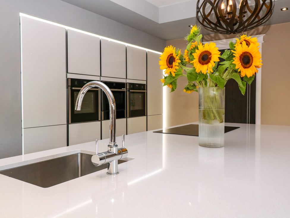 A kitchen with a sink and sunflowers in a vase at Thornbury in Barnard's Green, Malvern