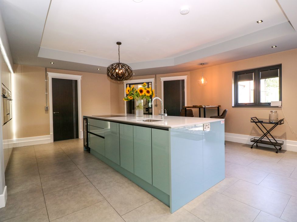 A kitchen with a large island and sunflowers at Thornbury, Barnard's Green, Malvern