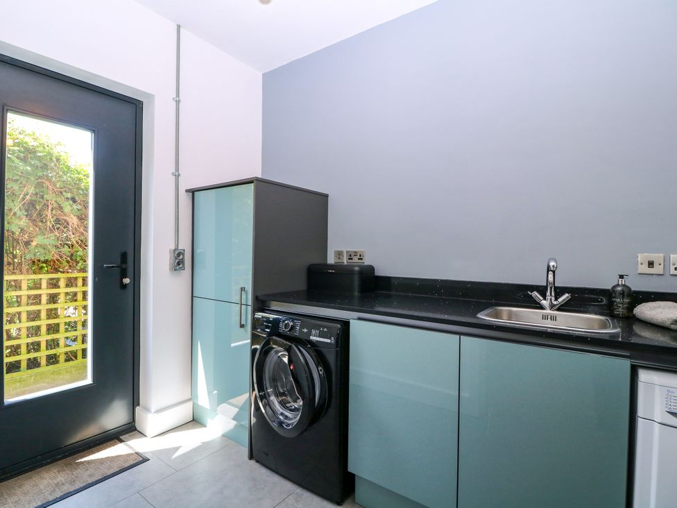 A laundry room with a washer and sink at Thornbury Barnard's Green, Malvern