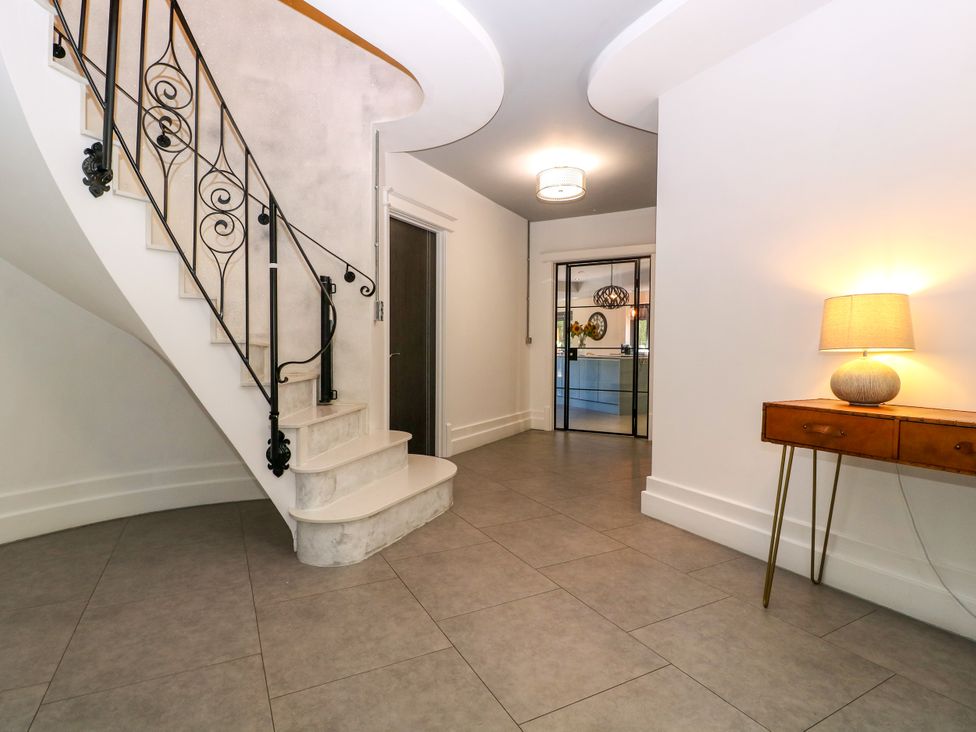 A hallway with a staircase and lamp at Thornbury, Barnard's Green, Malvern