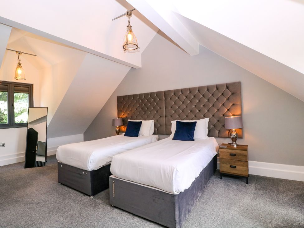 A bedroom with two beds and a lamp at Thornbury, Barnard's Green, Malvern