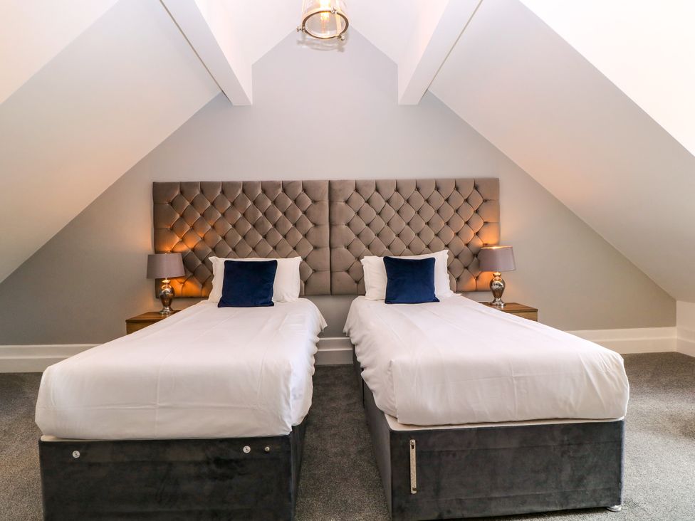 A bedroom with two single beds and bedside tables at Thornbury, Barnard's Green, Malvern