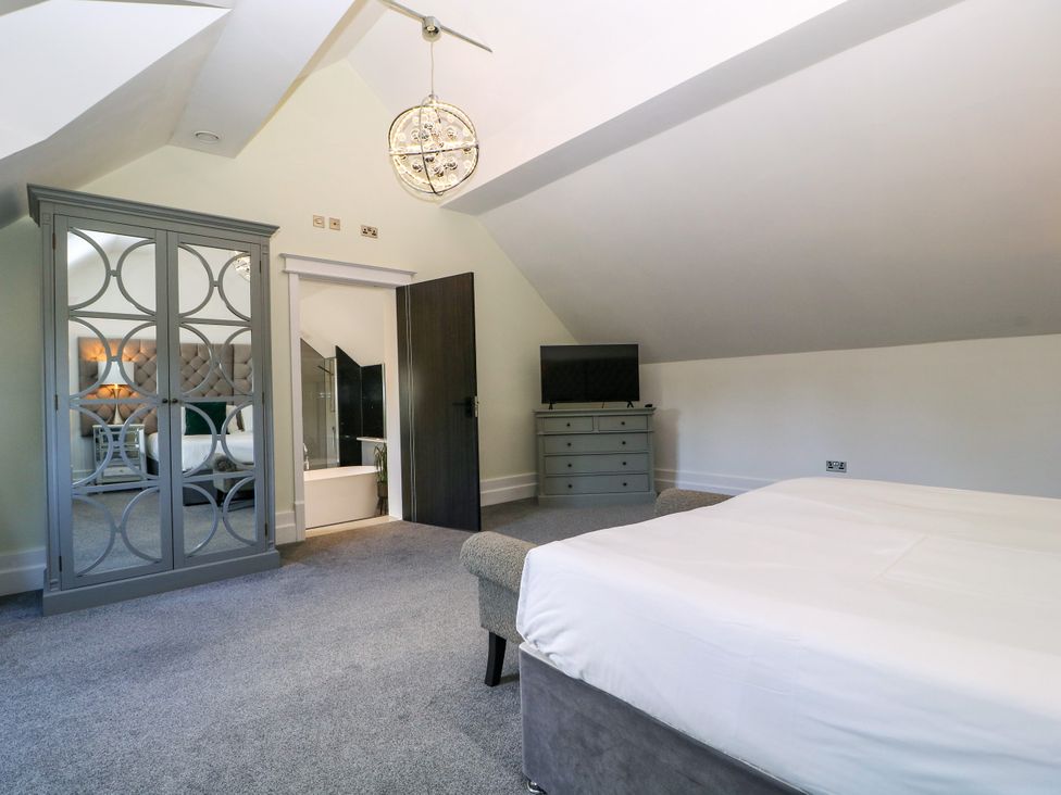 A bedroom with a bed, dresser, and television at Thornbury in Barnard's Green, Malvern