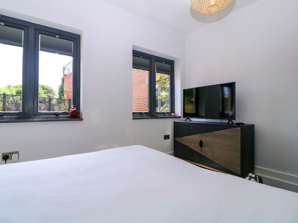 A bedroom with a television and windows at Thornbury in Barnard's Green, Malvern