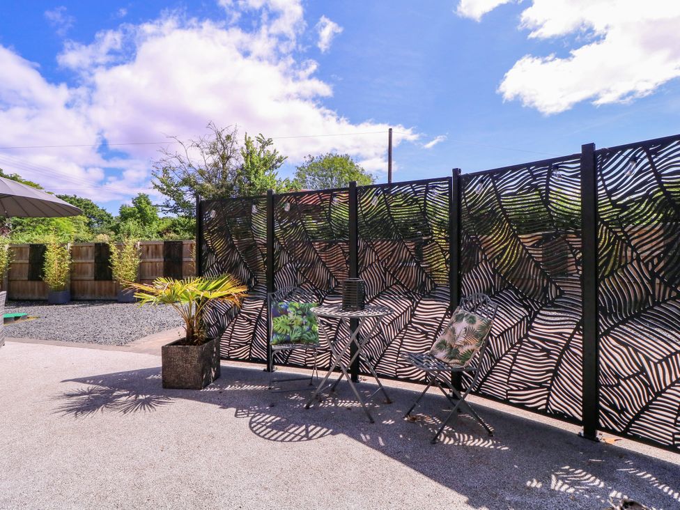 A garden with a table and chairs by a decorative fence at Thornbury, Barnard's Green, Malvern