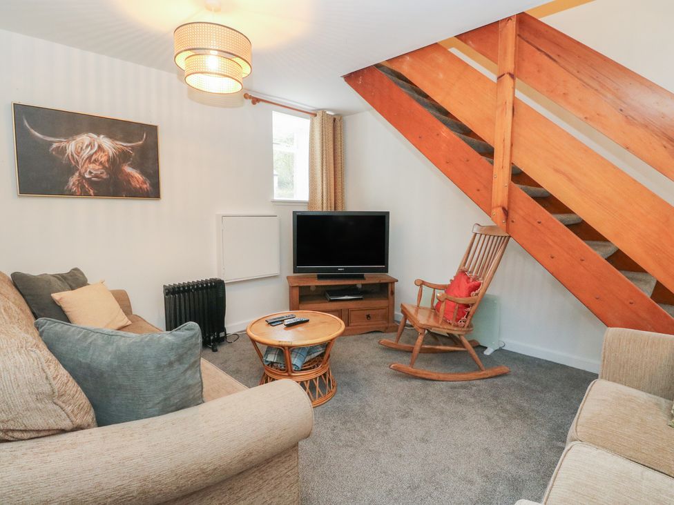 A living room with a television and a rocking chair at Willow Killean Farmhouse Cottages near Inveraray