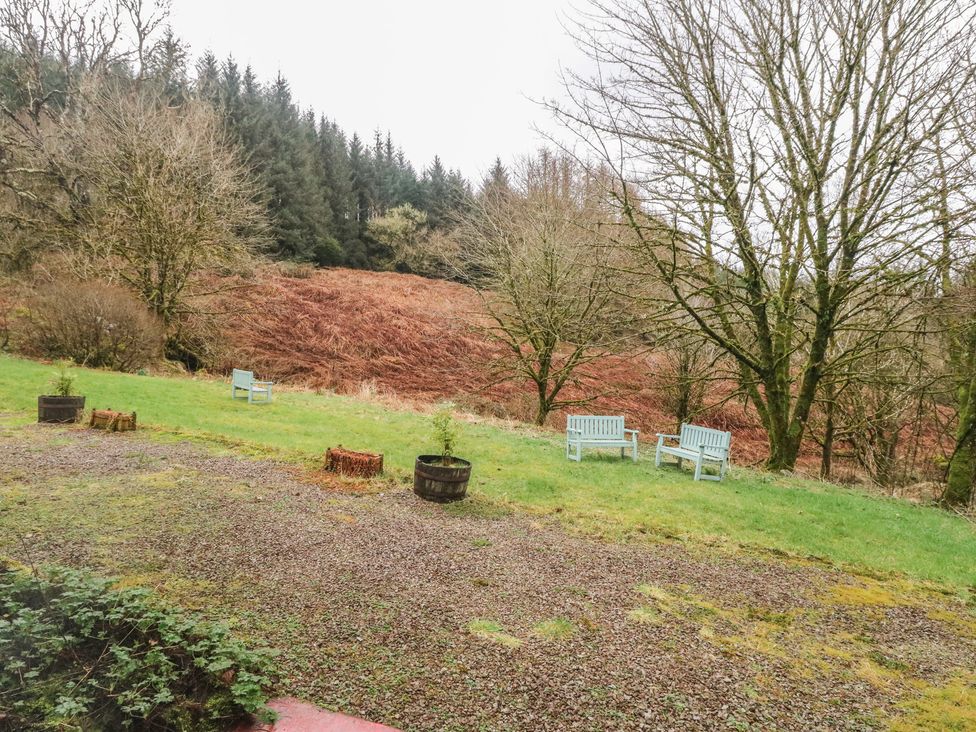 An outdoor area with benches and a grassy field at Willow Killean Farmhouse Cottages near Inveraray