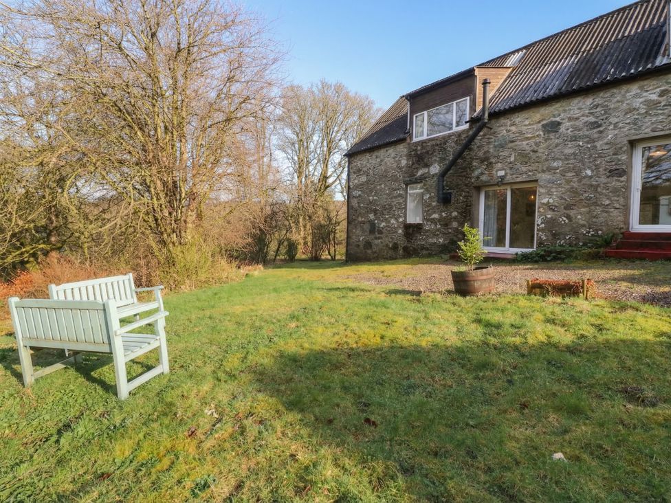 A garden with a bench and trees at Willow Killean Farmhouse Cottages near Inveraray