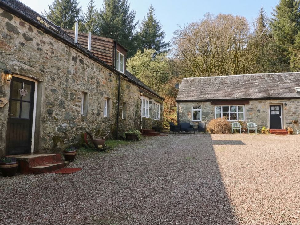 An outdoor area with stone buildings and seating at Willow Killean Farmhouse Cottages near Inveraray
