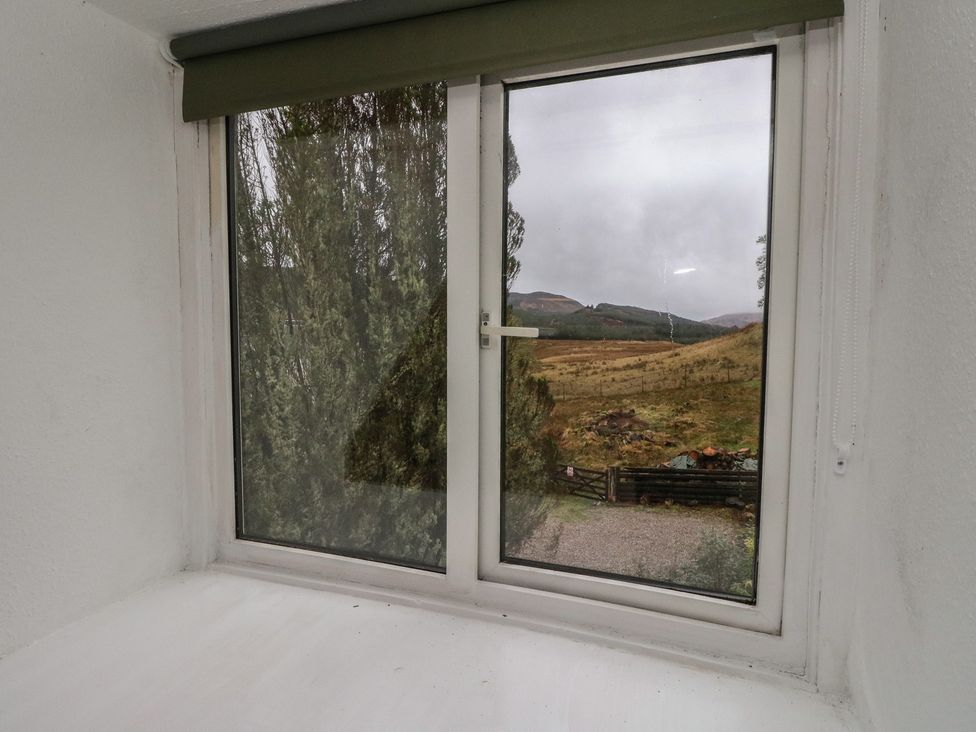 A window with view of trees and mountains at Hawthorn near Killean Farmhouse Cottages near Inveraray