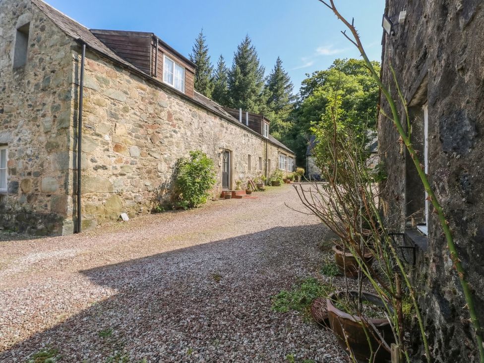An outdoor area with stone buildings and a gravel path at Hawthorn near Killean Farmhouse Cottages Inveraray