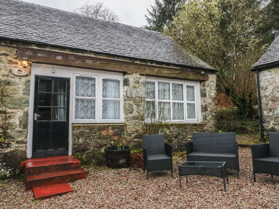 An outdoor view of a cottage with seating at Holly Cottage near Killean Farmhouse Cottages near Inveraray