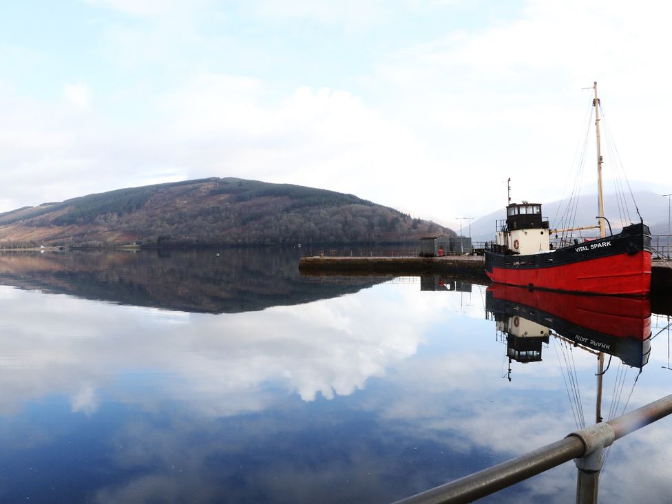 A boat on water reflecting mountains and sky at Holly Cottage near Killean Farmhouse Cottages